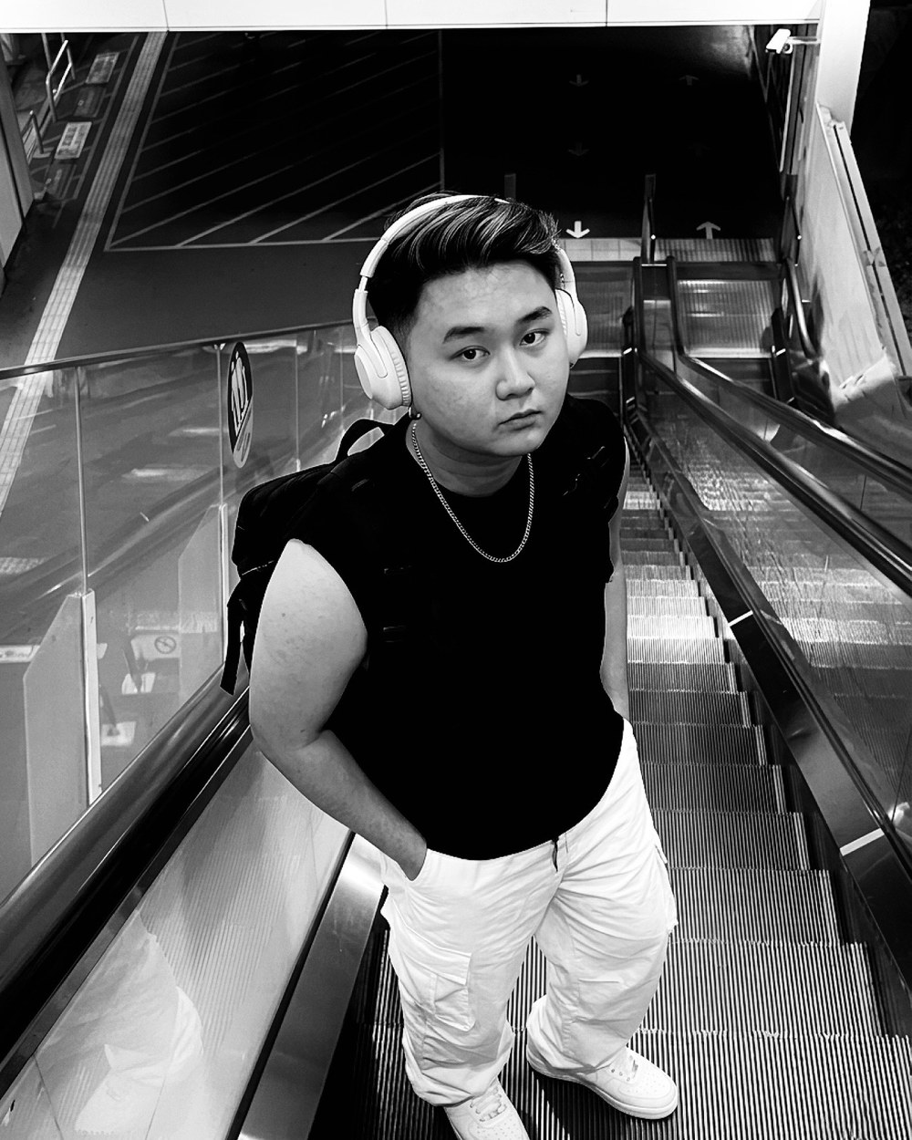 D standing on escalator with headphones