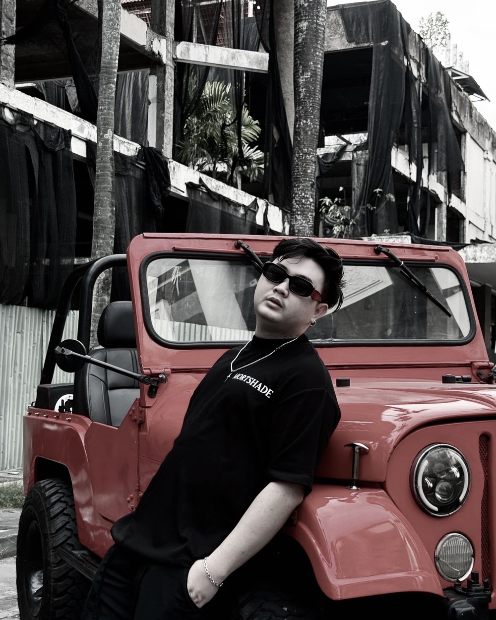D leaning against a red jeep